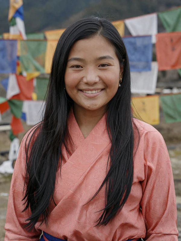 Tashi, 27-year-old Bhutanese entrepreneur from Thimphu in coral kira with prayer flags
