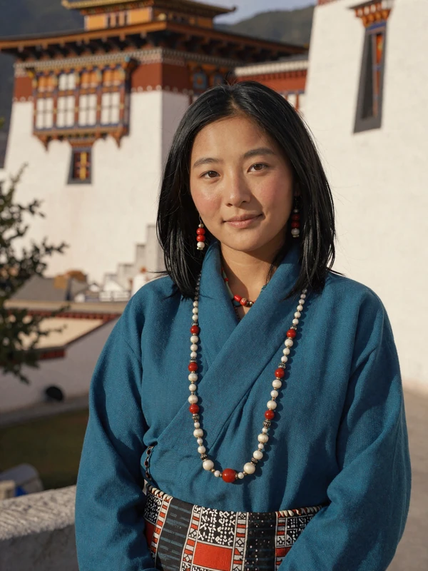 Pema, 26-year-old Bhutanese teacher from Paro in traditional teal kira near historic dzong